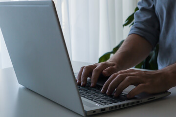 Hands of an adult man working on laptop. Work from home minimalism interior