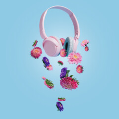 Pink headphones with lilac and violet Gerbera flowers flying against bright blue background. Colorful floral spring arrangement. Stereo sound and music. Creative music or flower bloom concept.