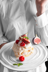 Woman holding a pig plate with meringue roll decorated with berries and figs