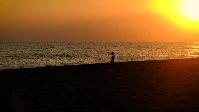 The girl takes a selfie at sunset on the sea. Selective focus.