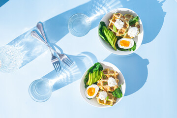 Belgian waffles with cream cheese, egg and avocado in a white plate. Healthy breakfast