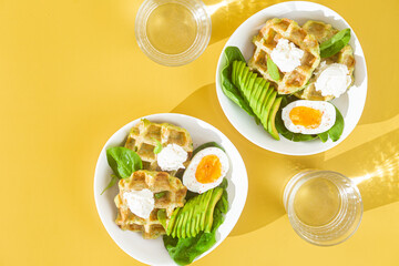 Belgian waffles with cream cheese, egg and avocado in a white plate. Healthy breakfast