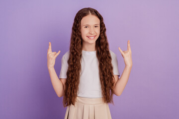 Photo of brown long haired girl make fingers rock symbol isolated on purple background