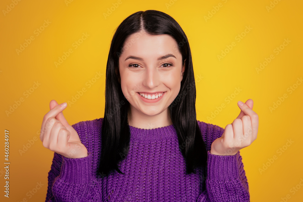 Wall mural photo of cheerful positive young lady beaming smile show money gesture isolated yellow color backgro