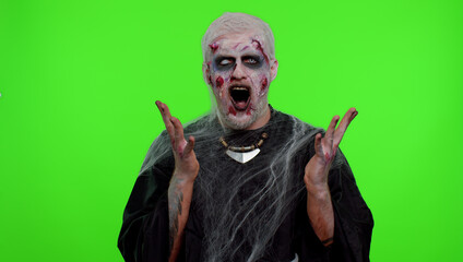 Dissatisfied frightening man with Halloween zombie bloody wounded makeup asking reason of failure, expressing disbelief irritation, feeling bored, disappointed in result, bad news. Sinister undead guy