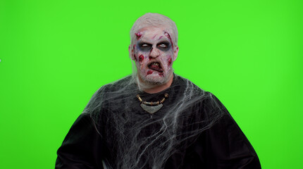 Sinister man with horrible scary Halloween zombie makeup making playful silly facial expressions...