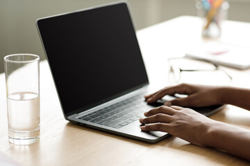 Teenage afro american girl pupil typing on laptop with empty screen, searching info