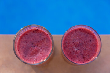 sweet pink fruit drinks and blue water by the pool minimalist food close-up for summer holidays