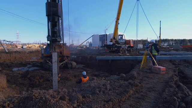 Excavation at a construction site, diesel pile driving machine with rumble and smoke drives piles deep into the ground to ensure the strength of the foundation of the future structure 