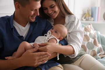 Happy couple holding their cute little baby with pacifier at home