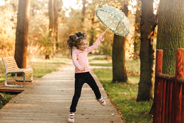 a little girl runs with an umbrella in her hands