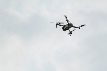 Fototapeta na wymiar Professional quadcopter flying high in the gray sky
