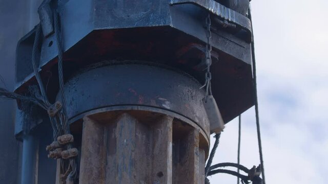 Excavation at a construction site, diesel pile driving machine with rumble and smoke drives piles deep into the ground to ensure the strength of the foundation of the future structure 