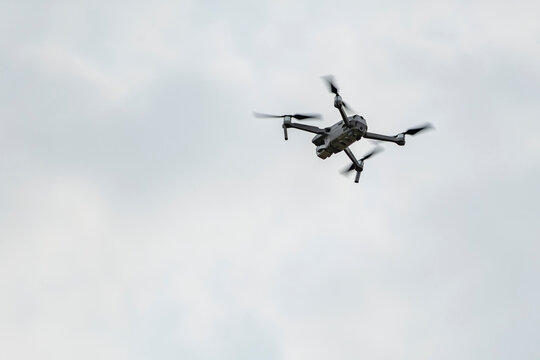 Professional quadcopter flying high in the gray sky