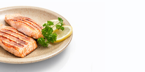 Grilled salmon fillet and lemon slices on a plate. White background. Healthy food. Isolate. Photo