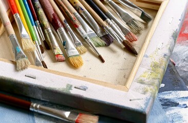 Various paint brushes on painted canvas  - 460289914