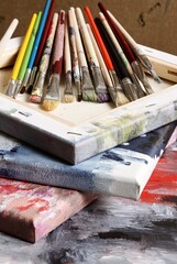 Various paint brushes on painted canvas- 460289917
