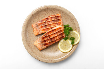 Grilled salmon fillet and lemon slices on a plate. White background. Healthy food. Isolate. Flat lay. Photo