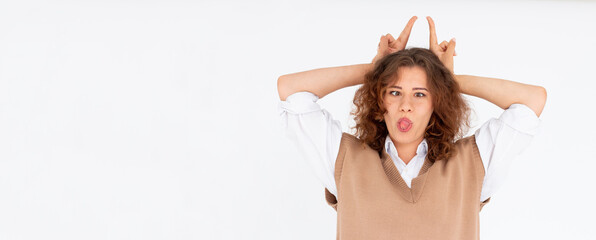 Pretty young woman with tongue out gesturing bunny ears and looking at camera on the white background.