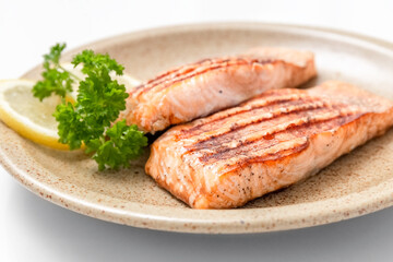 Grilled salmon fillet and lemon slices on a plate. White background. Healthy food. Isolate. Photo