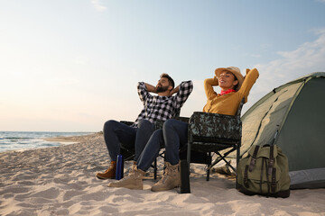 Couple resting near camping tent on beach