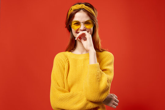 woman in yellow glasses with a bandage on her head yellow sweater Hipster red background