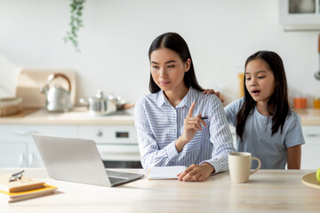 Bored asian girl demanding attention from her busy mother, woman working at home and ignoring her lonely child