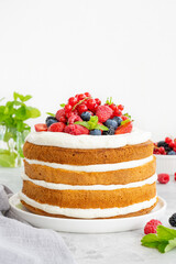 Homemade naked layered vanilla cake with whipped cream and fresh berries on top on a gray concrete background. Summer cake. Copy space.