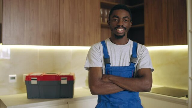 Confident plumber crossing arms on chest and smiling, high quality services