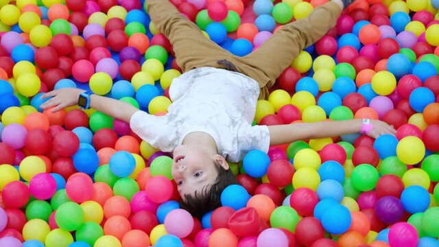 Boy falling down into pool with colored balls, autism spectrum disorder