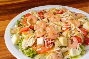 Shrimp and cheese salad on a white plate over wooden table.