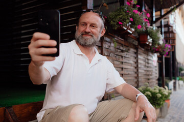Funny old man taking selfie by cellphone. Summer holiday