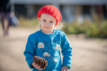 Niña con gorro de lana rojo jugando al aire libre en otoño - obrazy, fototapety, plakaty