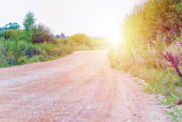 Empty Winding dirty rural not asphalted road which is passing in countryside.Sunset or sunrise.