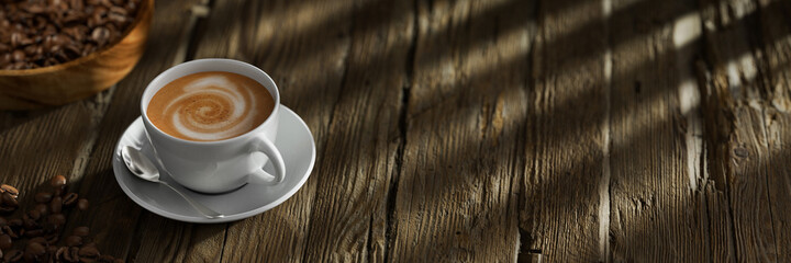 Frische Tasse Kaffee auf Tisch aus Holz mit Kaffeebohnen