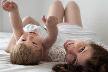 Obraz na płótnie Canvas Madre embarazada sonriendo mostrando su panza y jugando con su hijo