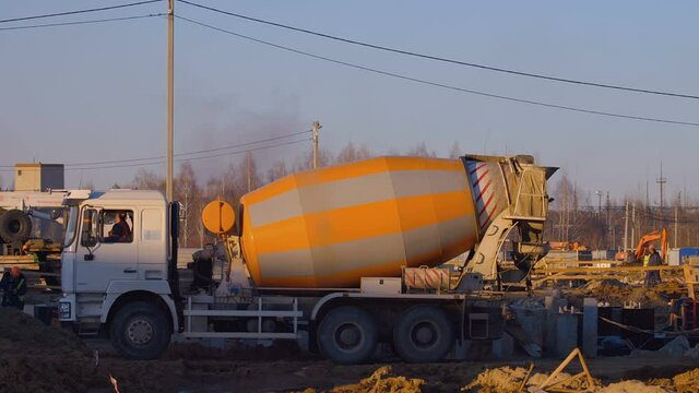 Excavation at a construction site, the concrete truck is moving in reverse to the place of pouring cement, the driver looks carefully in the mirrors