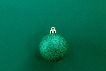 Christmas ball against emerald green background, selective focus