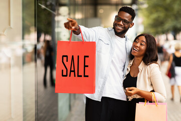 Portrait of couple showing shopping bag with sale inscription