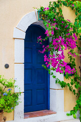 Fototapeta na wymiar Colorful blue door of traditional greek house with yellow walls at Asos village. Assos peninsula famous and extremely popular travel destination in Cephalonia, Greece, Europe.