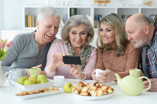Two senior couples using smartphone during morning tea