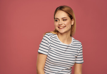 cute blonde girl in striped t-shirt emotions posing studio pink background