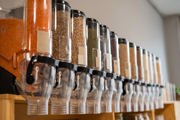 A woman fills a jar with red lentils. Selling bulk goods by weight in an eco store. Trade concept...