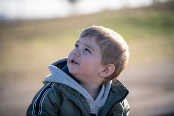 Niño rubio con campera jugando en el parque en invierno