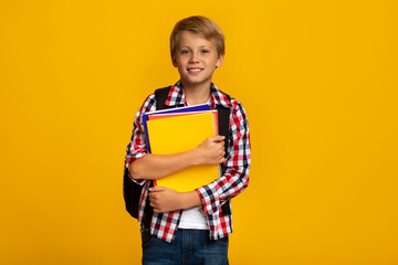 Smiling calm european young boy with books and notebooks ready to study