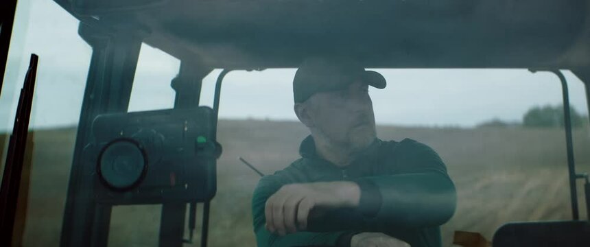 Portrait of 50s Caucasian male farmer driving a tractor through the field. Shot with 2x anamorphic lens
