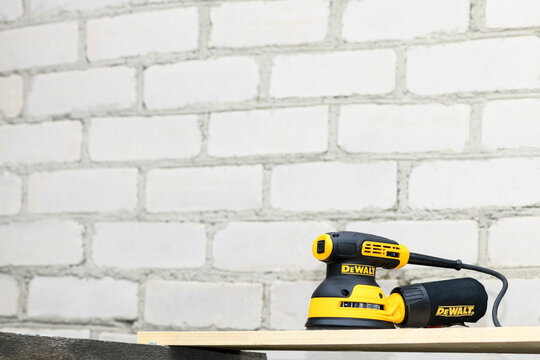 Editorial use only; Eccentric orbital sander DeWalt, grinder machine for wood on a brick wall background, copy space, Chelyabinsk, Russia - September 15, 2021