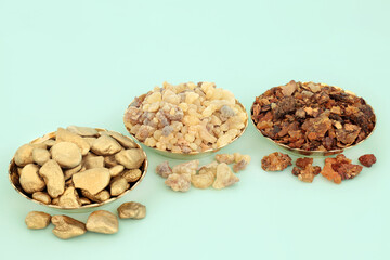 Gold frankincense and myrrh composition in bowls and loose. Symbols of gifts in the Christian religion given to Jesus Christ at his birth by the Three Wise Men. On pastel turquoise background.