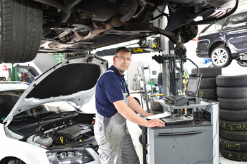 car mechanic maintains a vehicle with the help of a diagnostic computer - modern technology in the...