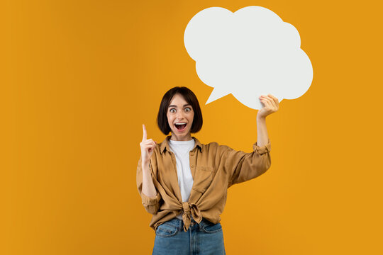 Aha moment. Inspired lady having idea, holding blank speech bubble and pointing finger up, showing empty space
